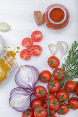 Bunch of tomatoes with garlic, rosemary, curry and chili pepper on white background