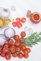 Bunch of tomatoes with garlic, rosemary, curry and chili pepper on white background