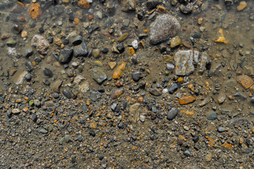 Stone background. Wet ground and stones. Natural background. Stony ground. Puddle. Stony soil. Gravel
