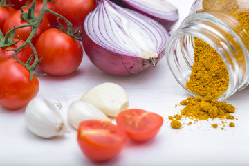 Bunch of tomatoes with garlic, rosemary and curry on white background