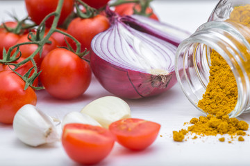 Bunch of tomatoes with garlic, rosemary and curry on white background