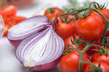 Bunch of tomatoes with garlic, rosemary and red onion on white background