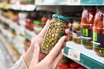 Hands with can of canned capers in store