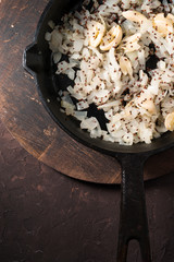 Fried onions, garlic and mustard seeds in a cast-iron frying pan free space. Indian food