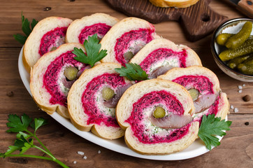 Sandwich with herring fillet, onion, pickled cucumber, cream cheese and beetroot