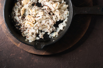 Fried onions, garlic and mustard seeds in a cast-iron frying pan. Indian food