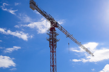 Tower building crane against the blue sky and sun. Construction of new buildings with a crane. Tower crane