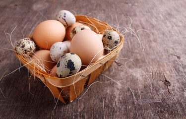 Fresh farmer eggs of chicken and quail in a basket on rustic background