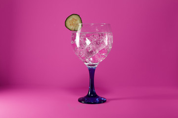 gin tonic with cucumber on pink