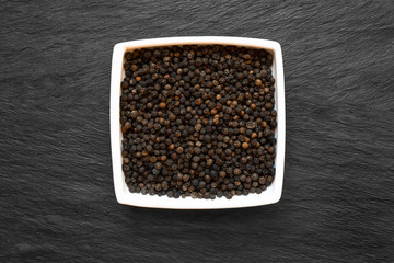 Black Pepper Grains in White Plate Placed on Black Stone Background Surface