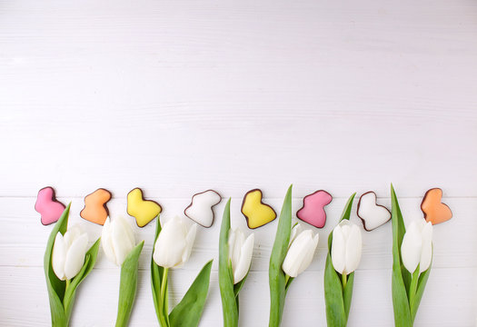 Frame of Sweets for celebrate Easter. Chocolate colorful bunny and white tulips. Copy space.