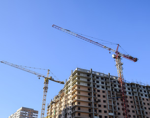 Tower building crane against the blue sky and sun. Construction of a new house. Construction of new buildings with a crane. Tower crane