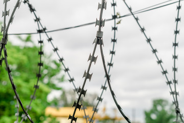 A barbed wire against the gray sky. Protective metal fencing. Selective focus