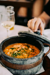 National cuisine of Cape Verde: Cachupa in traditional stone bowl. White wine glasses in background