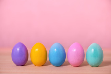row multi colored painted Easter eggs over pink background, festive greeting card