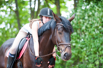 Young teenage lady-equestrian embracing her favorite frend-chestnut horse.