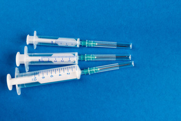 Medical syringes of different capacities lie on a blue surface.
