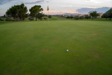 Obraz premium Golf ball on green fairway blue cloudy summer sky in the background
