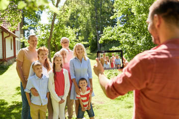 technology, generation and people concept - man taking picture of happy family by tablet pc computer in summer garden