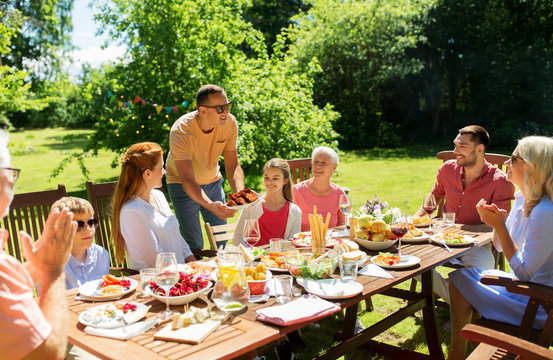 leisure, holidays and people concept - happy family having festive dinner or barbecue party at summer garden