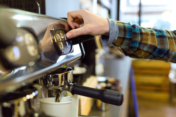 Waitress making coffee with professional machine in a coffee shop.