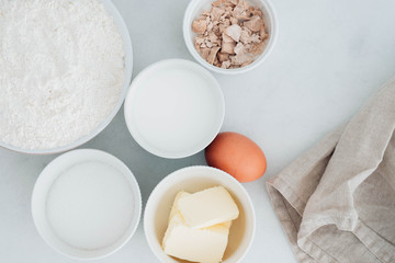 Preparation of the dough. The rolled out dough with the ingredients - flour, eggs,  and cooking instruments . On a white wooden background. Top view