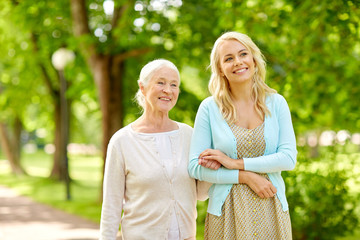 family, generation and people concept - happy smiling young daughter with senior mother at park