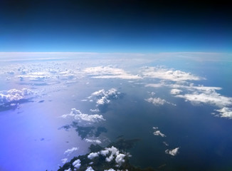 aerial view of the Mediterranean sea taken from an airplane with dark blue sky and clouds reflected on the water and an island in the bottom of the image