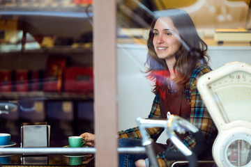 Beautiful young saleswoman relaxing and drinking coffee in organic shop.