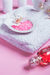 Obraz na płótnie Canvas Spa background, flat lay layout with pink sea salt, candles and aroma oils and cosmetic care products on a pink background