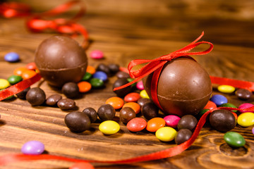 Chocolate easter eggs and multicolored candies on wooden table