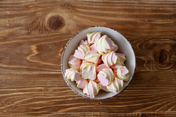  pink marshmallows in a white porcelain bowl on a wooden table