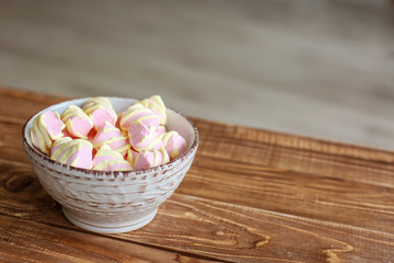  pink marshmallows in a white porcelain bowl on a wooden table