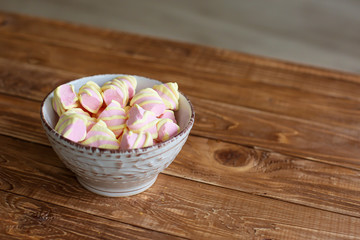 Obraz na płótnie Canvas pink marshmallows in a white porcelain bowl on a wooden table