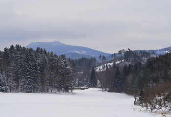 winter forest countryside snow covered landscape, trees and hill with lookout tower in luzicke hory mountain