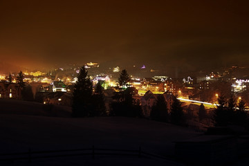 Fototapeta na wymiar Ski village at night with slope lights, Carpathians