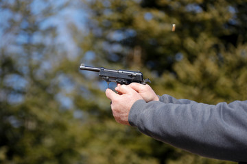 Close-up of a handgun being fired; ejected shell in the air.