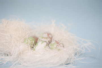 Easter background: pastel eggs on white straw nest with delicate floral doodles and cute bunny handpainted. Baby blue backdrop, candy pink and green gradients Soft blurred wallpaper.