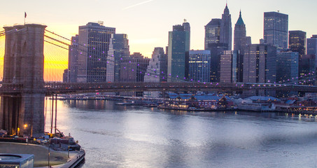 Naklejka premium Lights of New York City and Brooklyn Bridge at Sunset