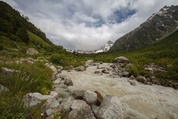 Fototapeta na wymiar Movement of clouds and water flows in a stormy river in the Caucasus mountains in summer