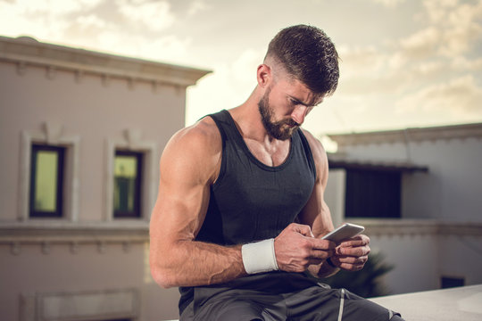 Handsome man using smartphone after sports training outdoors