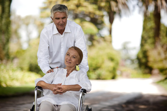 Senior man pushing his wife in a wheelchair.