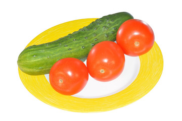 Cucumbers and red tomatoes on yellow plate isolated on white background