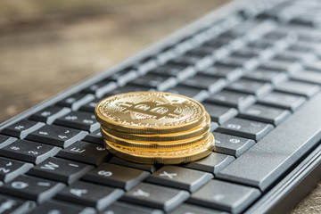 Side view of golden bitcoins on a wireless keyboard