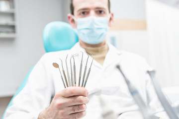 Fototapeta premium Set of dental instruments in the hand of a dentist blur in the background