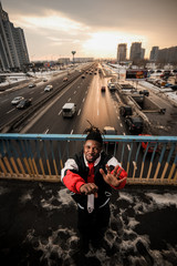 Young afro-american man emotionally gesturing on the background of a city road