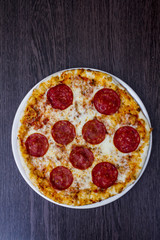 Pizza with salami on a black background top view