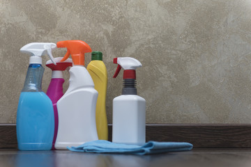 Bottles with cleaning agents, cleaning cloth on the tiled floor against the wall.