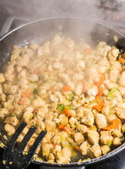 Cooking burrito in a pan with chicken, pepper, tomato for fajitas typical Latin America food