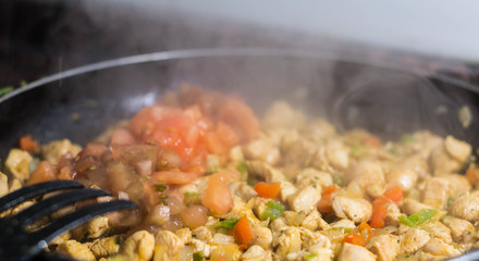 Cooking burrito in a pan with chicken, pepper, tomato for fajitas typical Latin America food